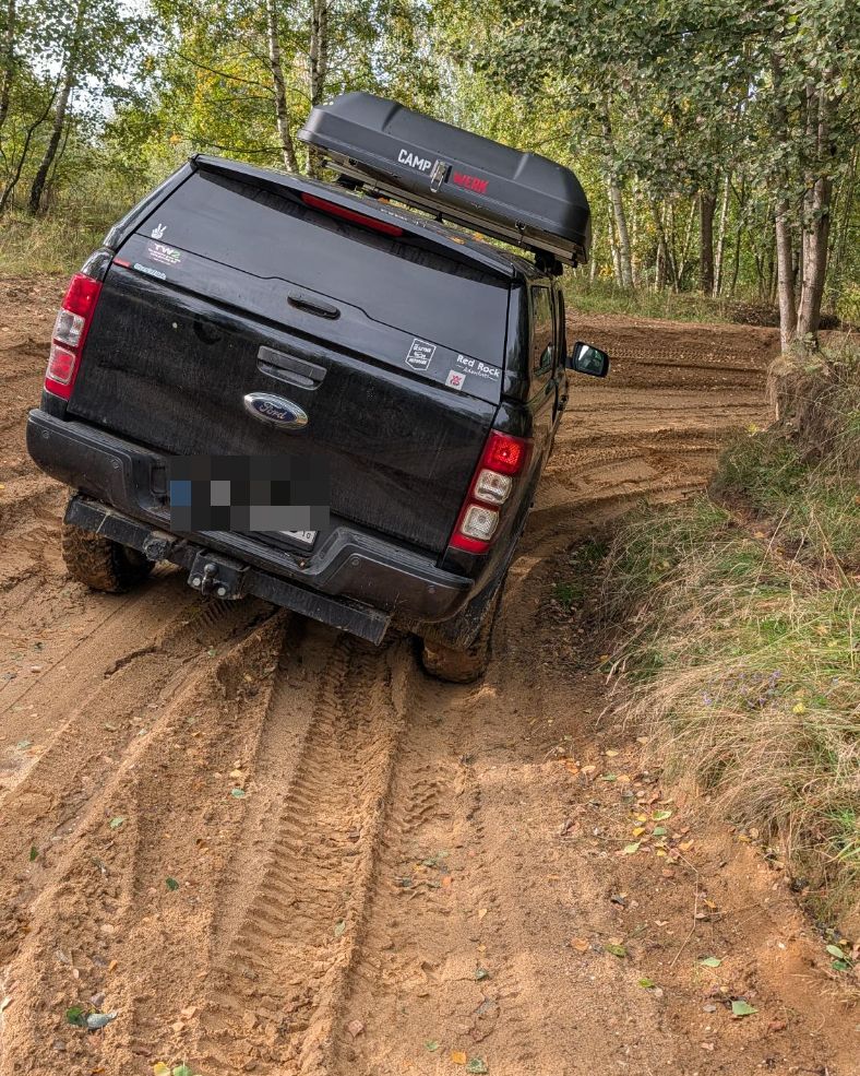 Ford Ranger von hinten in deutlicher Schräglage auf einer tief ausgefahrenen Sandpiste zwischen Birken