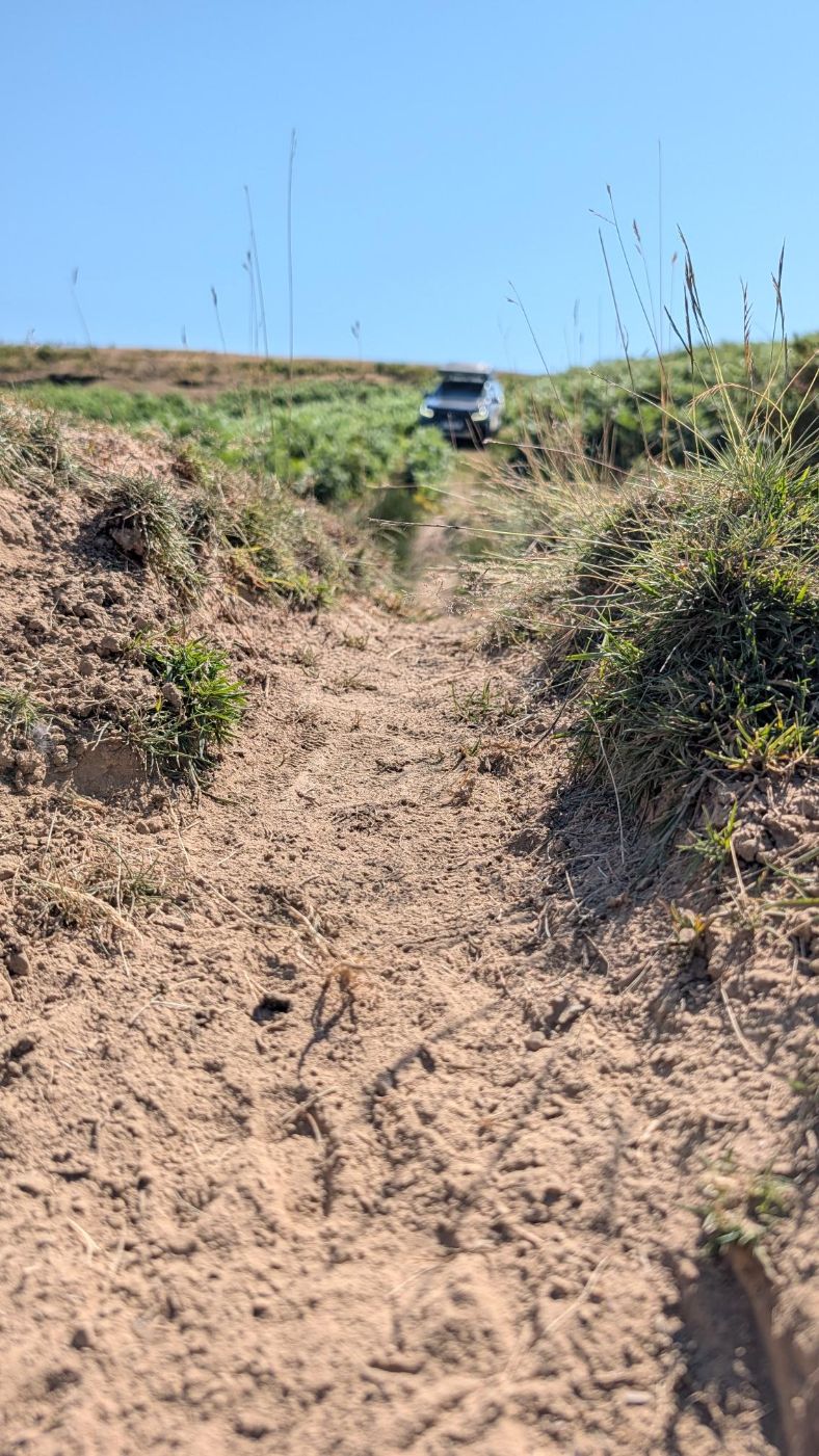 Ausgewaschene Offroad-Piste mit Ford Ranger im Hintergrund